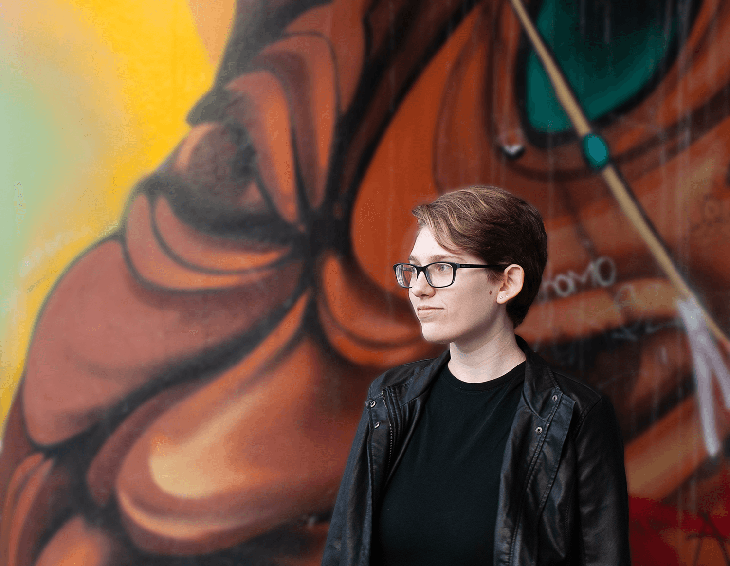 A portrait photograph of my friend standing in front of a mural.